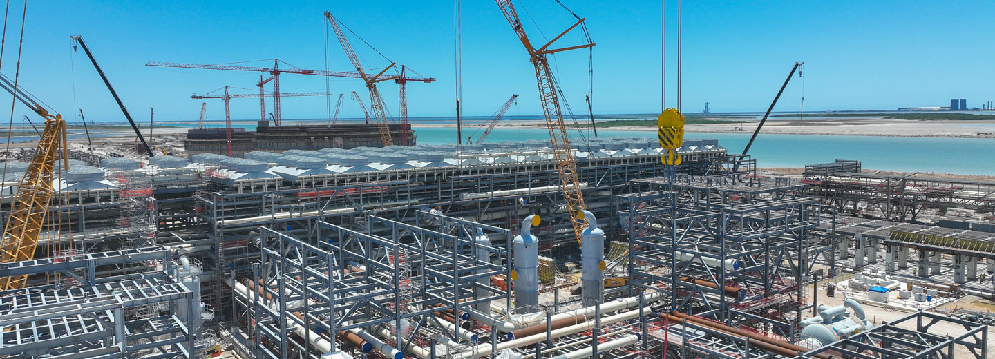 NextDecade's RGLNG terminal under construction with the coast and distant chemical refineries in the background