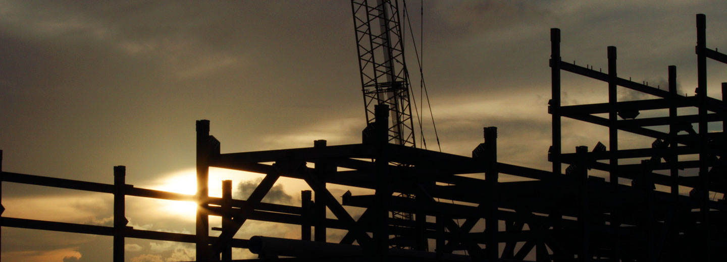 The late afternoon sun shining through steel frames of the RGLNG terminal under construction