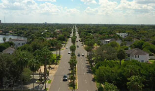 An aerial view of a main street surrounded by trees in Brownsville, Texas